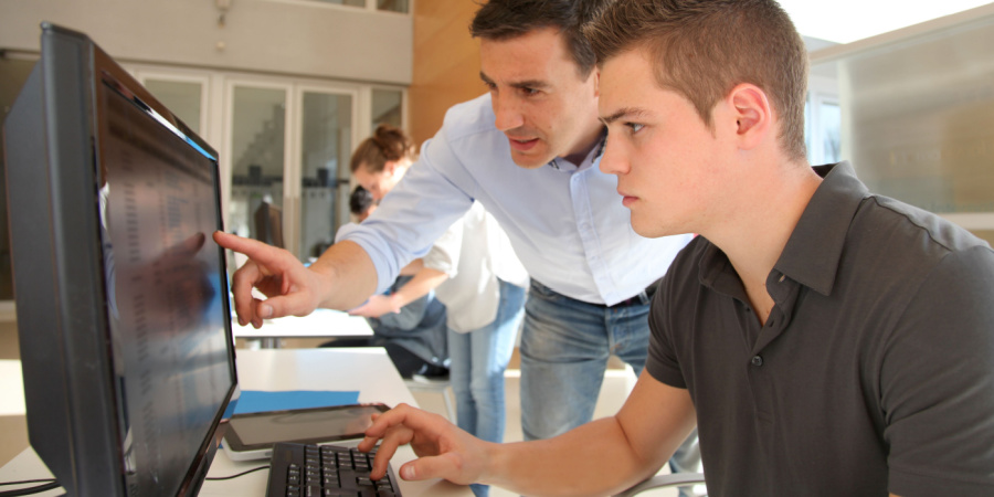 trainer and student looking at a computer screen | developing skills at scale